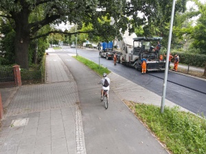 Nowy chodnik oraz droga rowerowa na ul. Dmowskiego - w tle pracownicy podczas układania nawierzchni