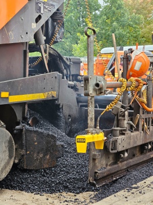 układanie masy bitumicznej na ul. Radosnej, widok na sprzęt budowlany 