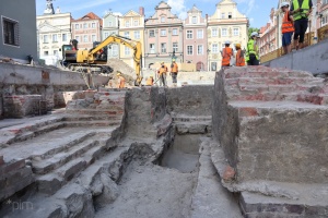 fragment murów fundamentowych na tle kamienic 